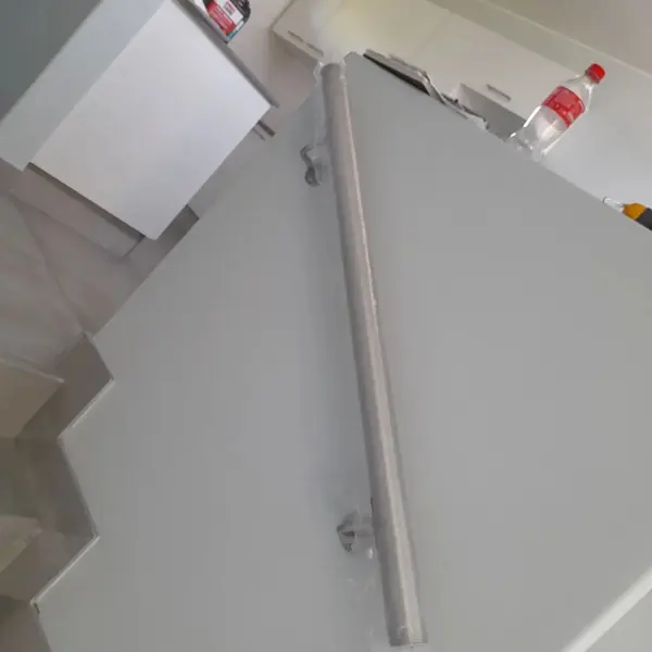 Handyman job: metal stair handrail on grey painted wall, bottle on ledge