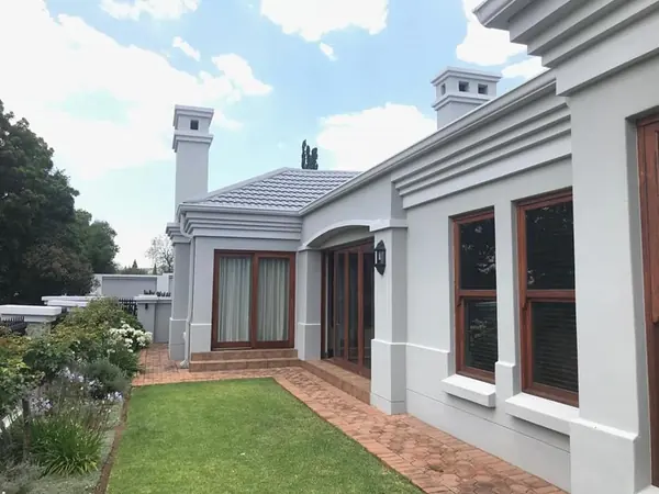 Painting job: repainted grey house exterior with chimneys, lawn and paving, blue sky