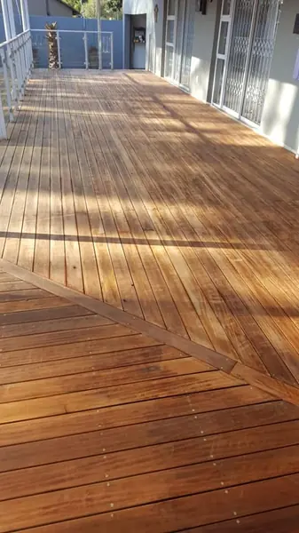 Painting job: large sunlit timber deck freshly oiled with diagonal border