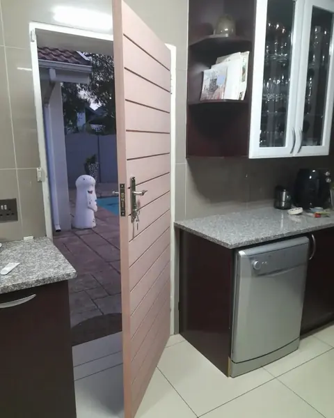Before. Painting job: pink slatted door open to patio, kitchen