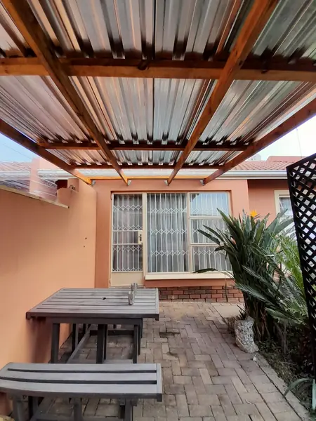 Renovations job: pergola over paved patio with table and benches, security-gated windows