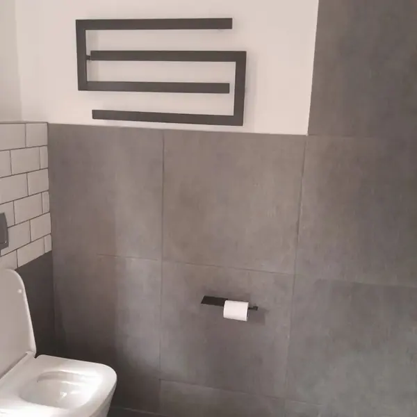 Renovations job: bathroom with grey wall tiles, toilet and towel rail